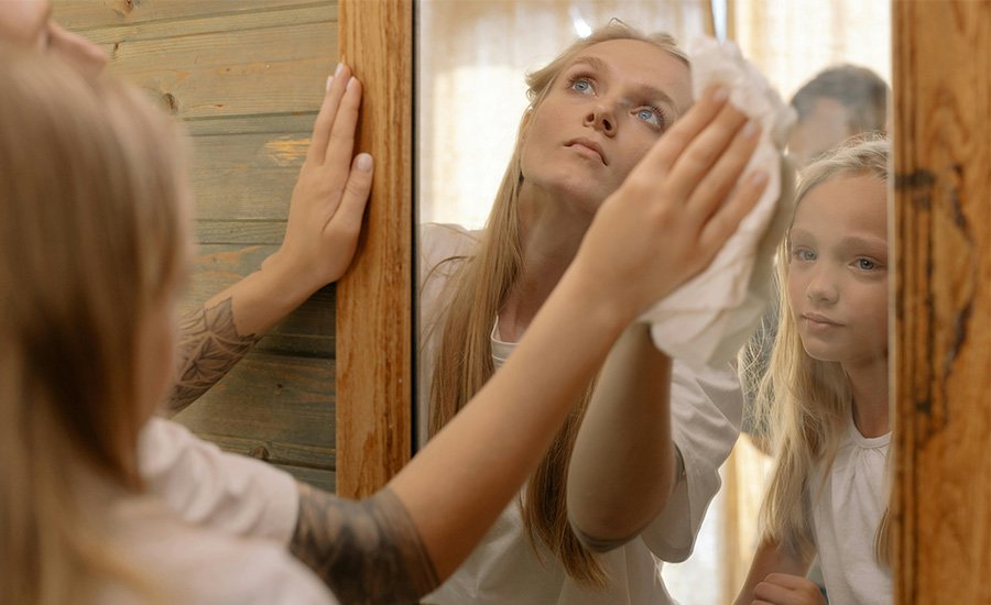 Mujer e hija mirandose a un espejo
